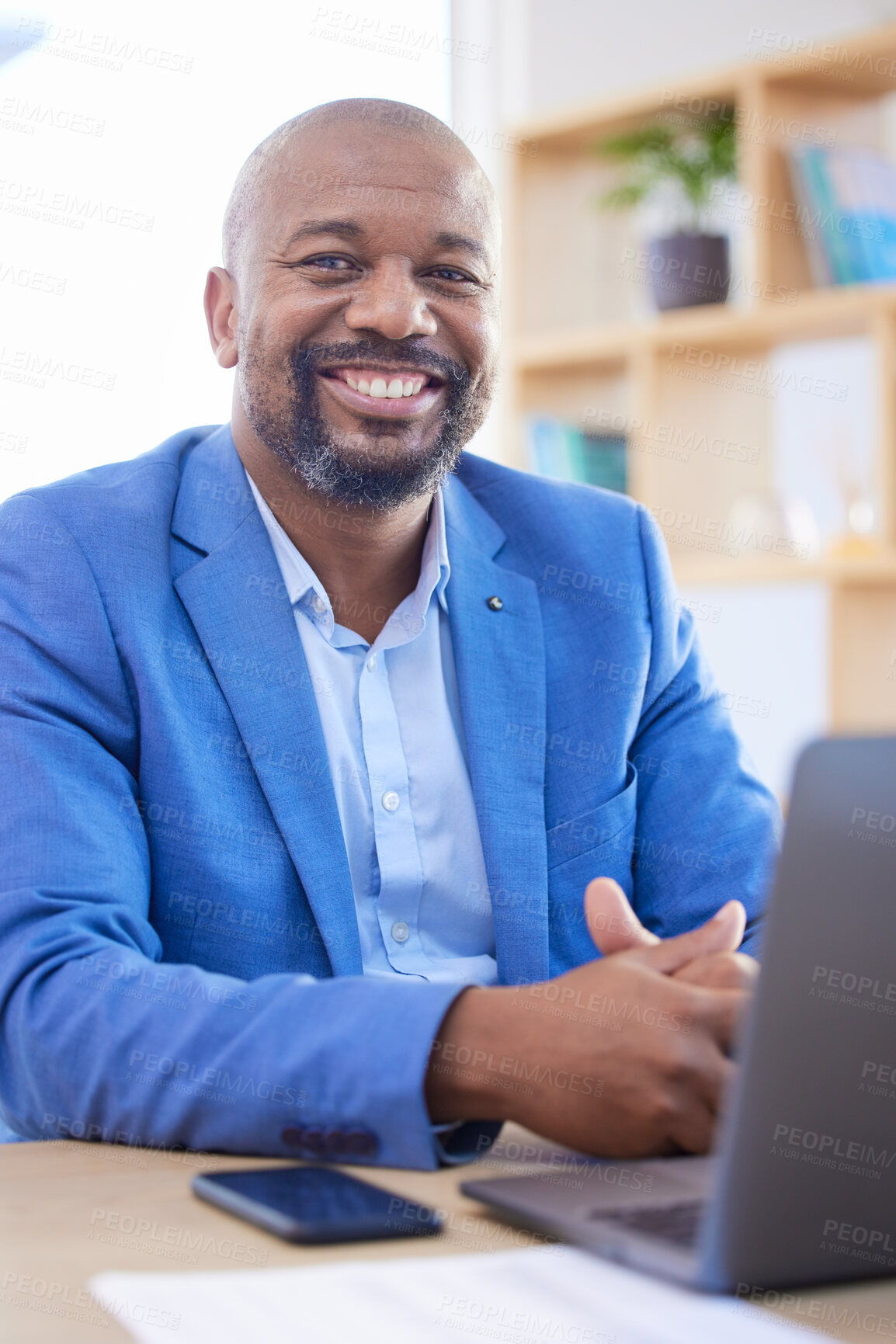 Buy stock photo Happy, smile and portrait of an African businessman sitting at his desk and working on a laptop in his office. Happiness, leader and black man leader planning management documents on computer.