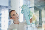 Happy, woman and cleaning window in home with cloth to wipe away water mark with proud smile. Housewife cleaner in Canada at transparent glass with detergent spray and chemical safety gloves.

