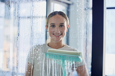 Buy stock photo Cleaning, window and glass with a woman using a tool in her home with water, soap or foam inside. Housework, smile and service with a young female cleaner wiping a transparent pane in a modern house