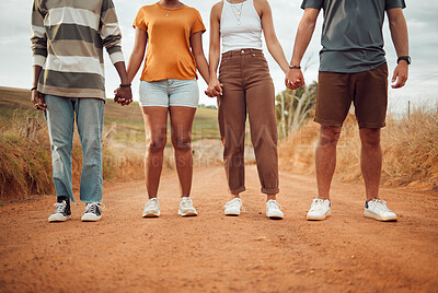 Buy stock photo Legs, diversity and people holding hands together in solidarity, connection or support. Trust, friendship help and outdoor desert group, team or friends walk, travel or stand in countryside dirt road