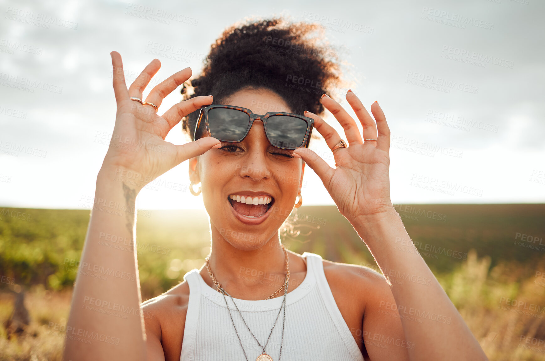 Buy stock photo Black woman smile, wink and happy on summer countryside nature holiday at sunset. Girl with fashion sunglasses, laugh with happiness and peace on relax travel vacation trip at South Africa wine farm 