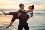 Man at beach lift woman with love, smile with sunset over the horizon or background. Young couple travel to ocean on vacation, happy together with sunset over sea or waves in nature during summer