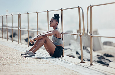 Buy stock photo Runner, ocean and thinking on rest while running in outdoor in the summer by the water. Black woman, athlete and training sitting by the sea to breathe, focus and calm after workout, run or exercise