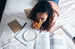 Bed, girl and student studying with pizza for lunch in her bedroom reading school for tests or exams at home. Female enjoys fast food and learning from a notebook and university or college textbooks