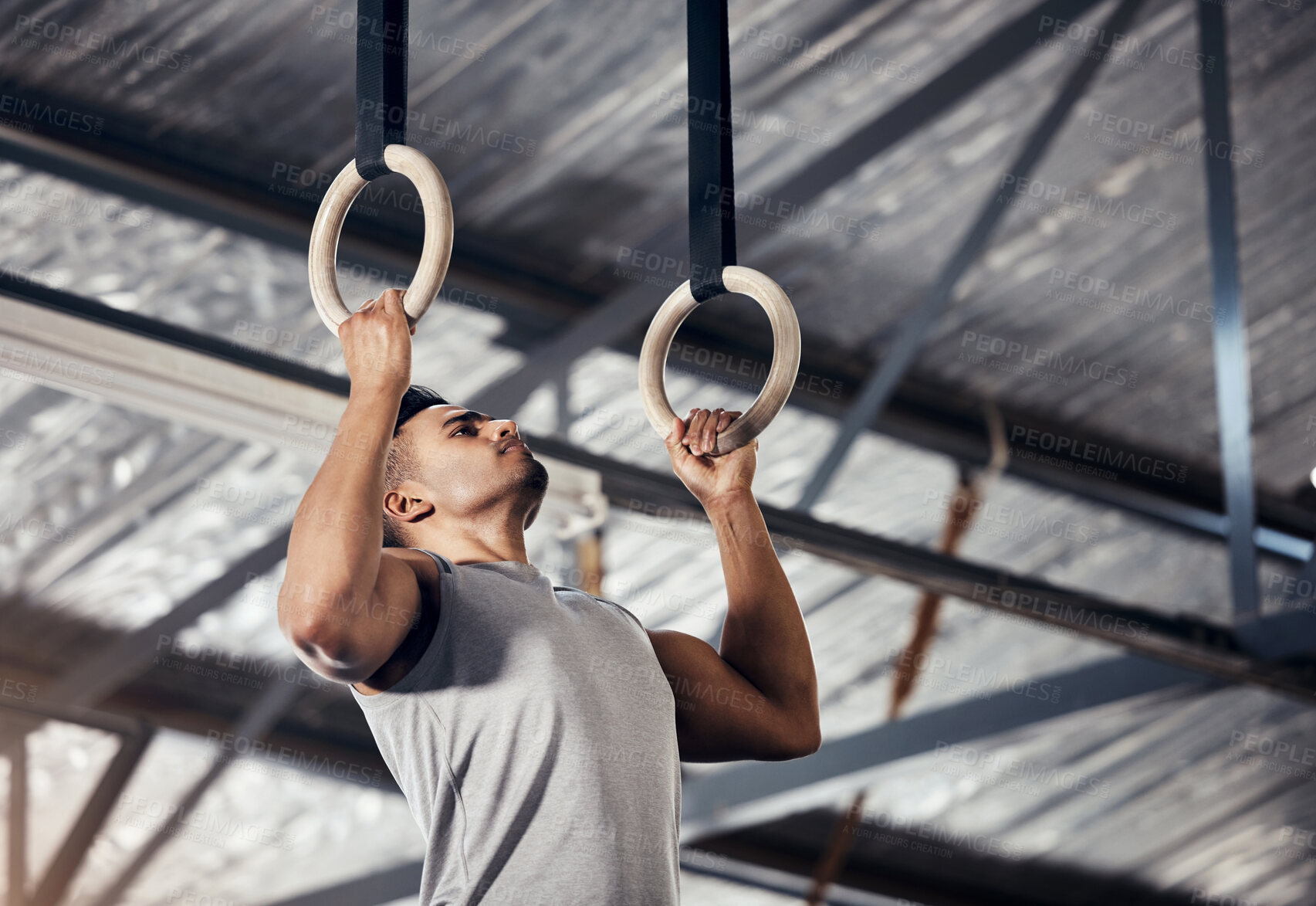 Buy stock photo Fitness, exercise man in gymnastics gym during pull up, training or exercise on rings. Young sports athlete or gymnast, strong mindset and start workout to improve muscle or cardio at sport club