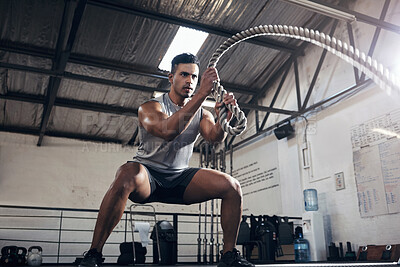 Buy stock photo Health, gym and battle rope workout with man at a fitness center, cardio and muscle training. Power, energy and exercise by muscular athlete focused on intense movement, strength and endurance