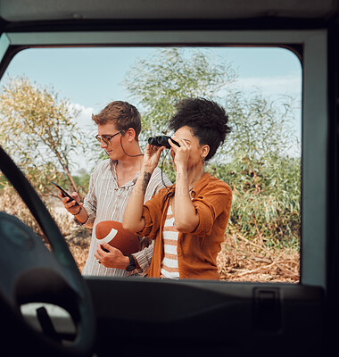 Buy stock photo Window, car and diversity couple on road trip journey to explore Australia safari, countryside or outdoor nature. Binocular, transportation adventure and man streaming football game on mobile phone