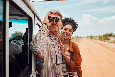 Buy stock photo Road trip, travel and view with a couple using binoculars for sightseeing while outdoor on sand road during their summer vacation. Diversity, love and holiday with a man and woman traveling on a trip