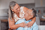 Hug, love and senior couple with smile for funny story while in the living room of their house. Happy, comic and elderly man and woman relax and hugging for support in the lounge of their home