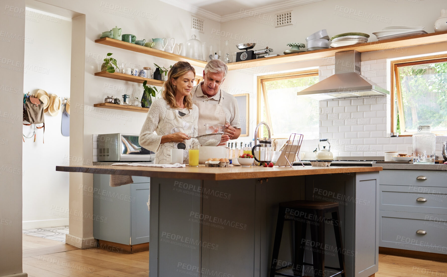 Buy stock photo Senior couple in the kitchen cooking together for a party, dinner or lunch in their modern home. Fun, dessert and elderly man and woman in retirement baking, bonding and talking in their house.