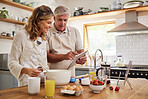 Cooking, tablet and old couple learning baking skills online at home kitchen in a lovely and romantic marriage. Recipe, eggs and elderly woman prepares strawberry cake, food and cookies with partner
