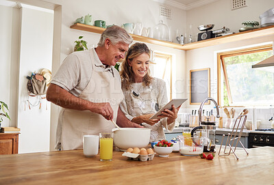 Buy stock photo Baking, tablet and retirement with a senior couple cooking in the kitchen of their home together. Love, food and technology with an elderly man and woman following an internet recipe in the house