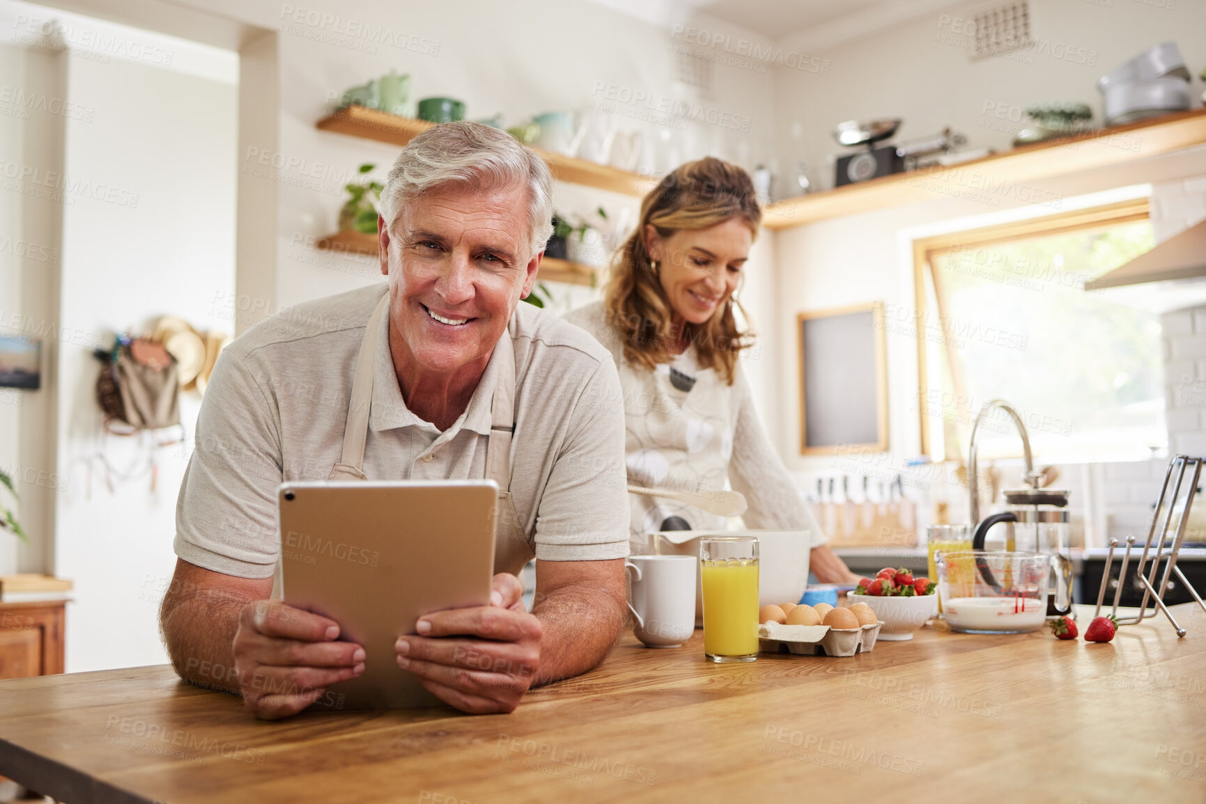 Buy stock photo Portrait, senior couple and cooking with tablet together in a modern kitchen of the home. Happy, retirement and elderly man and woman baking with ingredients, recipe and instructions on mobile device