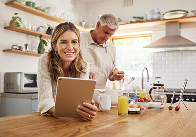 Buy stock photo Tablet, baking and retirement with a senior couple cooking in the kitchen of their home together. Food, technology and health with an elderly man and woman following an internet recipe to make a meal