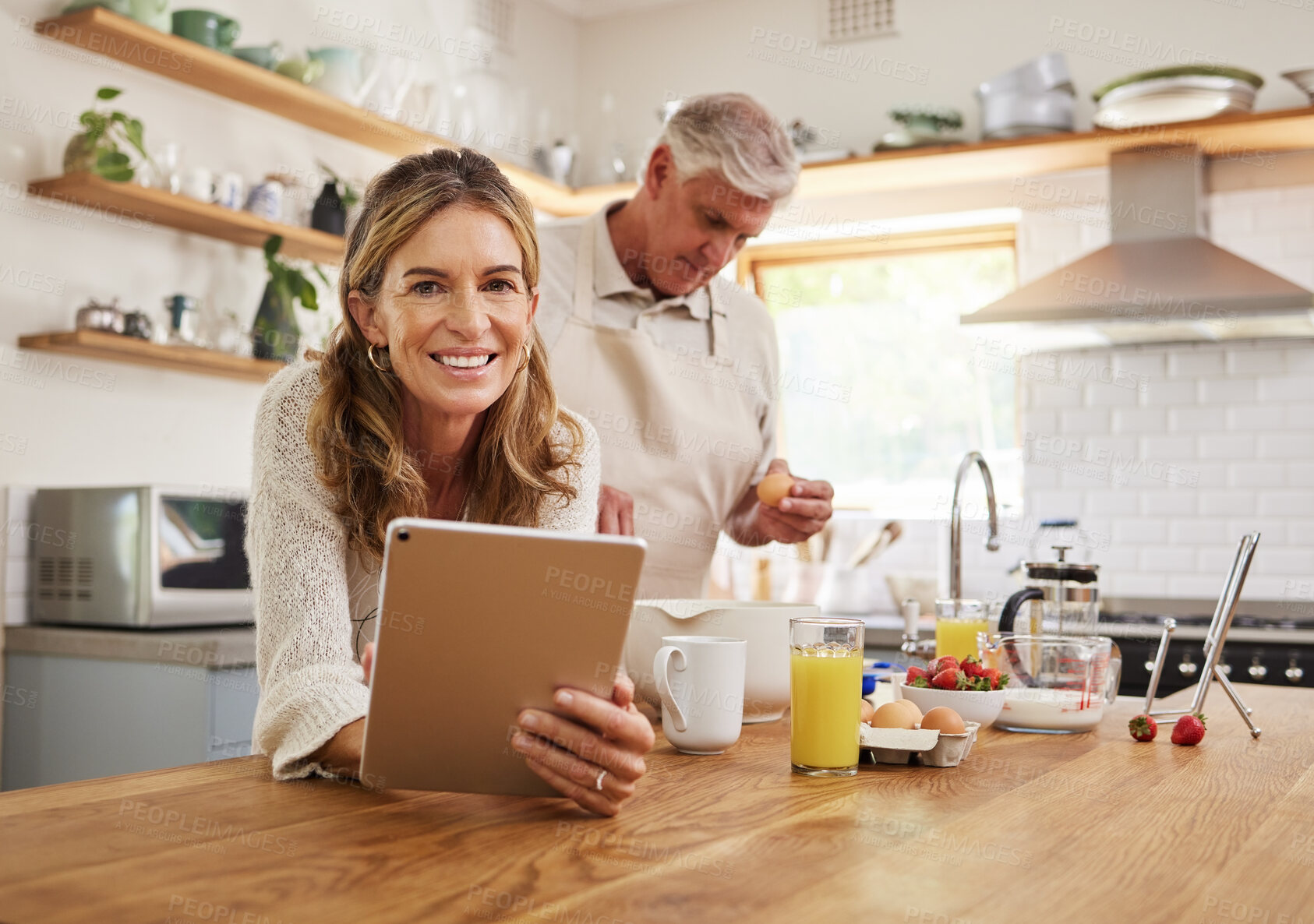 Buy stock photo Tablet, baking and retirement with a senior couple cooking in the kitchen of their home together. Food, technology and health with an elderly man and woman following an internet recipe to make a meal