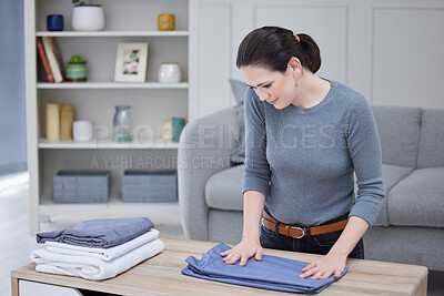 Buy stock photo Laundry, clean and woman folding clothes, linen and towel on a table in the living room of her house. Cleaner, worker or girl packing, cleaning and organizing clothing and fabric on a desk in lounge