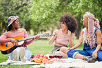 Music, comic and friends on picnic in a park with food and singing with a guitar together in summer. Funny, playful and African women with smile for musician, instrument and lunch on grass in nature