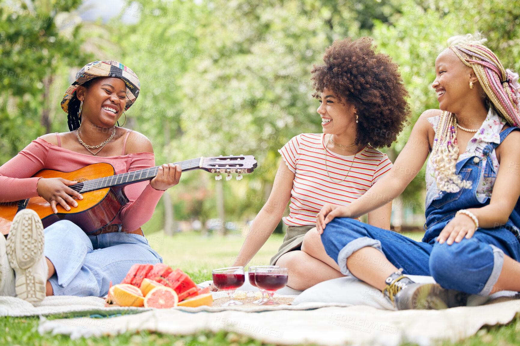 Buy stock photo Girl friends, music and guitar at picnic with fruit, drinks and happy laughter in nature. Friendship, song and party on grass, group of black women having lunch together on blanket in park in Africa.