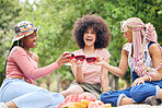 Black woman, cocktail and friends relax on picnic for peace, wellness and friendship reunion with alcohol glass drink. Nature park, trees and happy gen z people bonding, having outdoor fun and smile