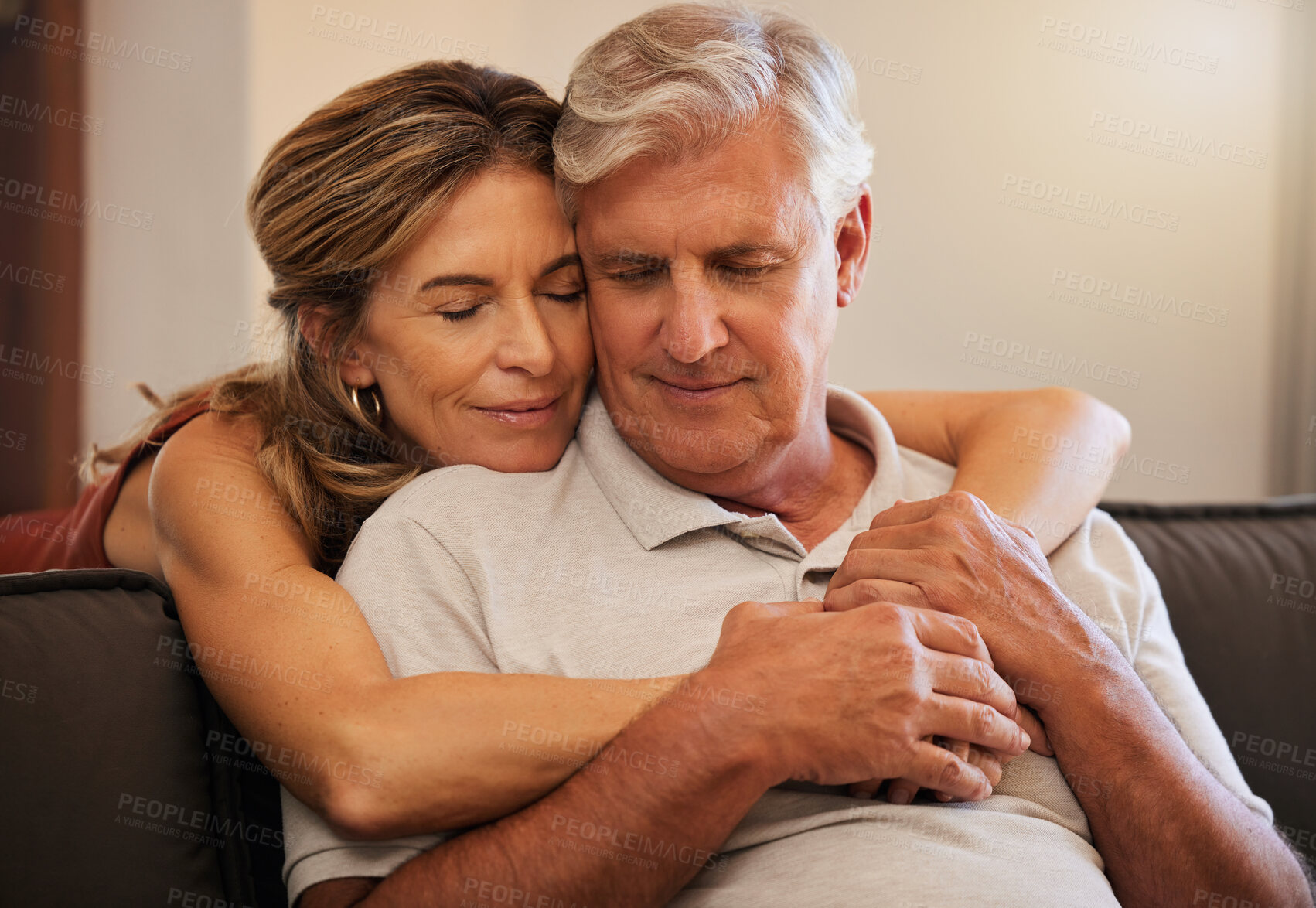 Buy stock photo Hug, love and senior couple giving support during retirement in the living room of their house. Happy elderly man and woman hugging in trust, help on sofa and happiness together in their home