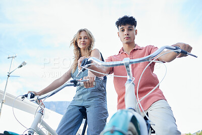Buy stock photo Bike, couple and carbon footprint with a man and woman riding a bicycle outdoor on a blue sky background from below. Portrait, travel and commute with a young male and female cycling on vacation