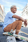 Relax, skateboard and city black man in street of California in summer with hipster fashion. Edgy, young and trendy African American skater male in the USA resting on urban road with smile.

