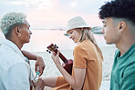 Young friends play music on beach, people on summer holiday and travel outdoor with guitar ukulele in Hawaii. Diversity students vacation together, relax at sea picnic and road trip celebration