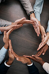 Hands, teamwork and synergy with business people in a circle or huddle as a team on a wooden table in the office. Collaboration, motivation and goal with an employee group working together on success