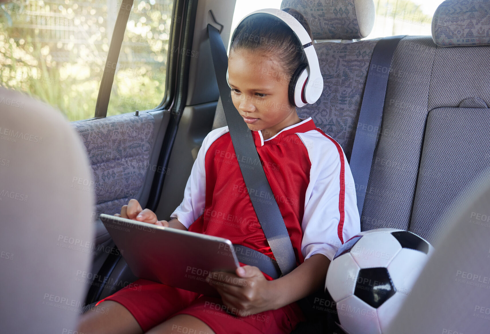 Buy stock photo Tablet, sports and relax child on car travel transportation to soccer, football or match game in SUV van with safety seat belt. Youth girl streaming video, subscription movie or use kid friendly app