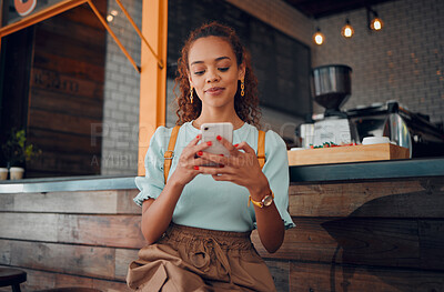 Buy stock photo Phone, social media and coffee shop with a woman typing a text message while sitting in a cafe to relax. Internet, mobile and communication with a young female customer in a restaurant texting