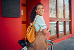 Happy, smile and woman with a bicycle in the city by a red building with a backpack on a walk. Happiness, cycling and girl from Mexico walking with a bike in the urban street while on summer holiday.
