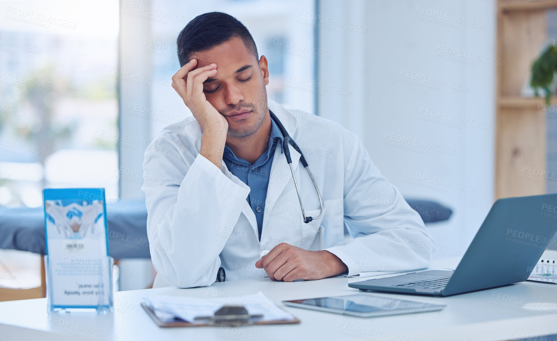 Buy stock photo Tired man in medical hospital, doctor napping at office desk and healthcare burnout in India. Exhausted stress nap from insomnia, sleeping male by laptop desk and mental health in doctors clinic