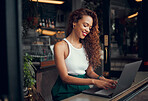 Laptop, internet cafe and typing with a black woman blogger working at the window of a coffee shop on an article or report. Computer, email and remote work with a female writer busy in a restaurant 