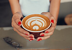 Cafe, coffee and woman hands with manicure holding drink cup for leisure break with top view. Coffee shop girl customer with cappuccino art and feminine red nail polish at table close up.