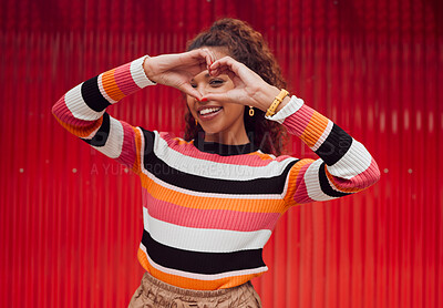 Buy stock photo Heart shape, hands and portrait of a happy woman in a studio with trendy, stylish and fashion clothes. Happiness, smile and love gesture with girl model from Puerto Rico standing by a red background.