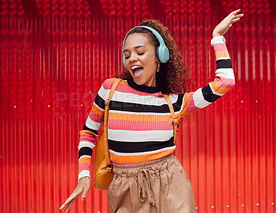 Buy stock photo Dance, music and freedom with a black woman on a red background outdoor for fun or movement. Radio, streaming and audio with a young female dancing while listening to a playlist on headphones