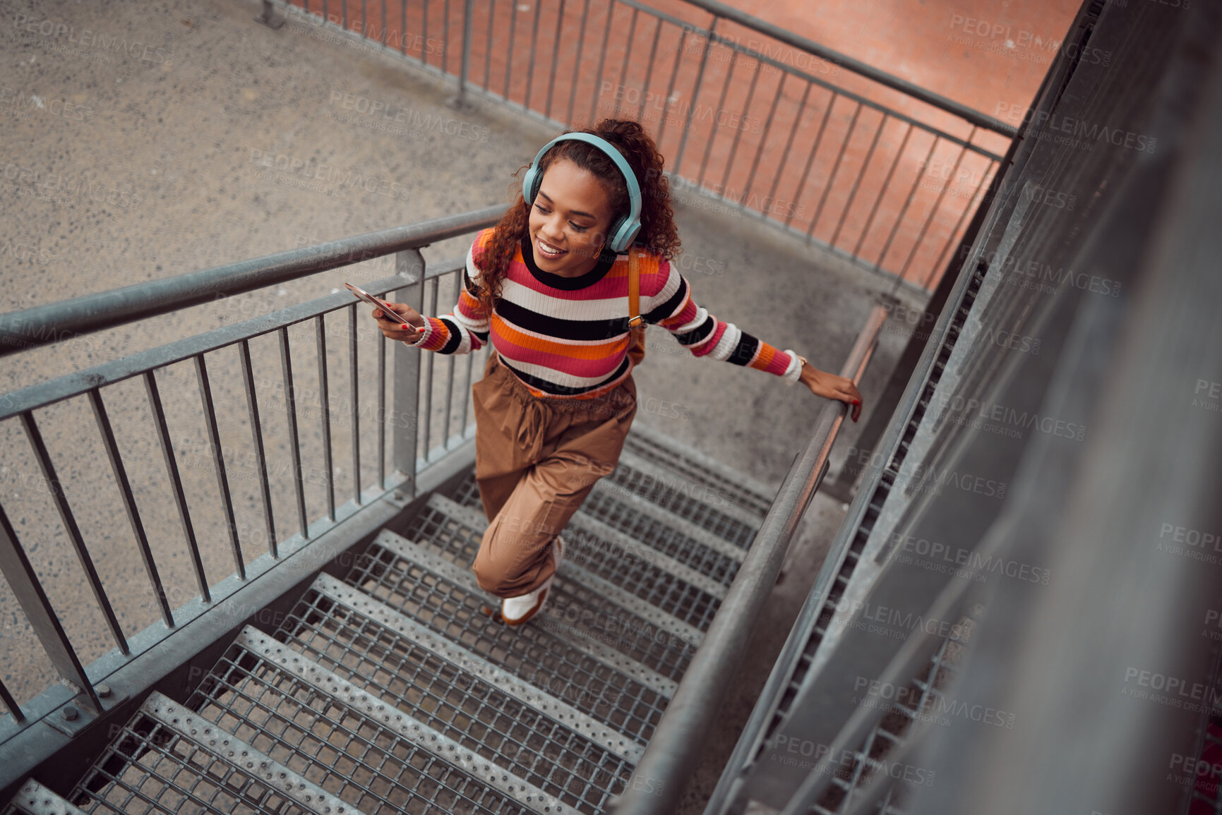 Buy stock photo City, music and girl on stairs, phone in hand and listening to audio. Happy black woman with headphones streaming song, track or radio on smartphone in urban town, student freedom on weekend