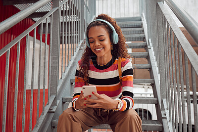 Buy stock photo Phone, headphones and black woman on stairs in city streaming music, audio or radio. Gen z, earphones and Brazilian student on 5g mobile, texting or internet surfing, social media or web browsing.