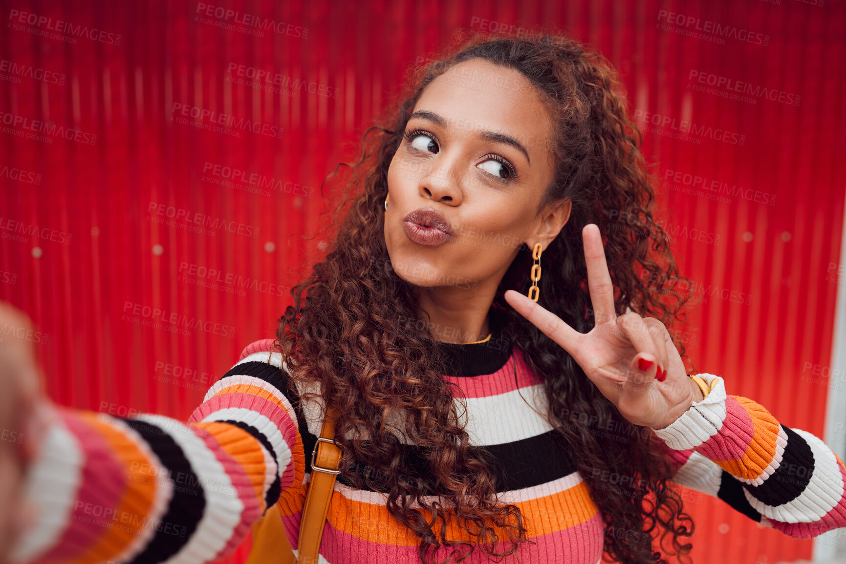 Buy stock photo Fashion selfie, peace sign and happy woman against a red wall in city for fun travel holiday. Portrait urban girl show cool hand gesture and lips while traveling and sharing picture on social media