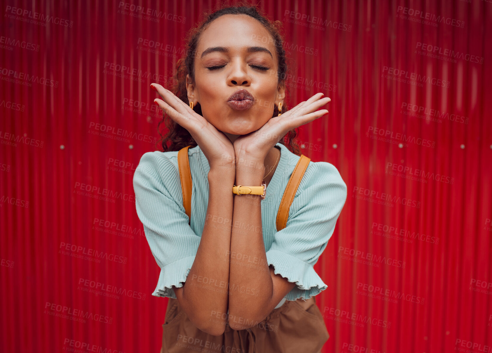 Buy stock photo Fashion, kiss and black woman being playful against a red wall in the city of Norway for travel. Face of a young, happy and pouting girl with luxury makeup, clothes and happiness on an urban holiday