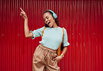 Music, dance and woman in the city against a red background during a travel holiday in Amsterdam in summer. Happy, smile and girl with freedom, 5g radio and singing with headphones on vacation