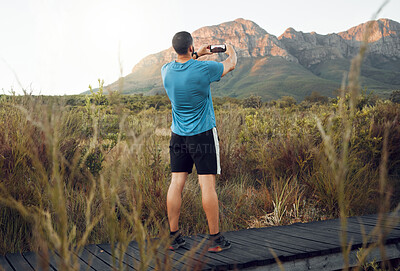 Buy stock photo Phone, nature and fitness with a man taking a photograph while out for a sports run in the wilderness with a view. Exercise, training and workout with a picture of the mountain taken by male athlete