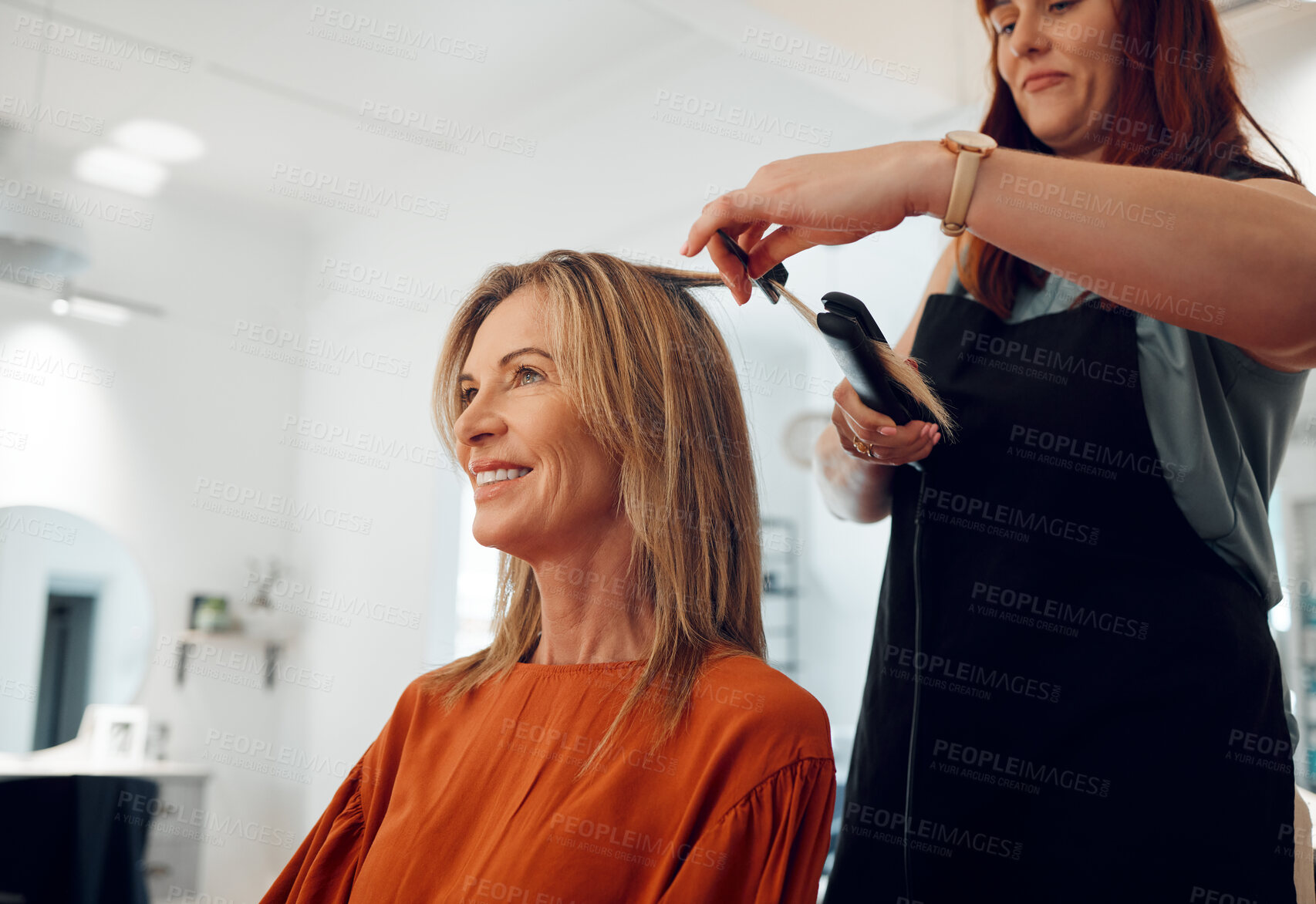 Buy stock photo Salon, haircut and style with a woman customer straightening her hair for beauty or wellness. Fashion, client and hair with a female hairdresser or beautician at work with a consumer for haircare