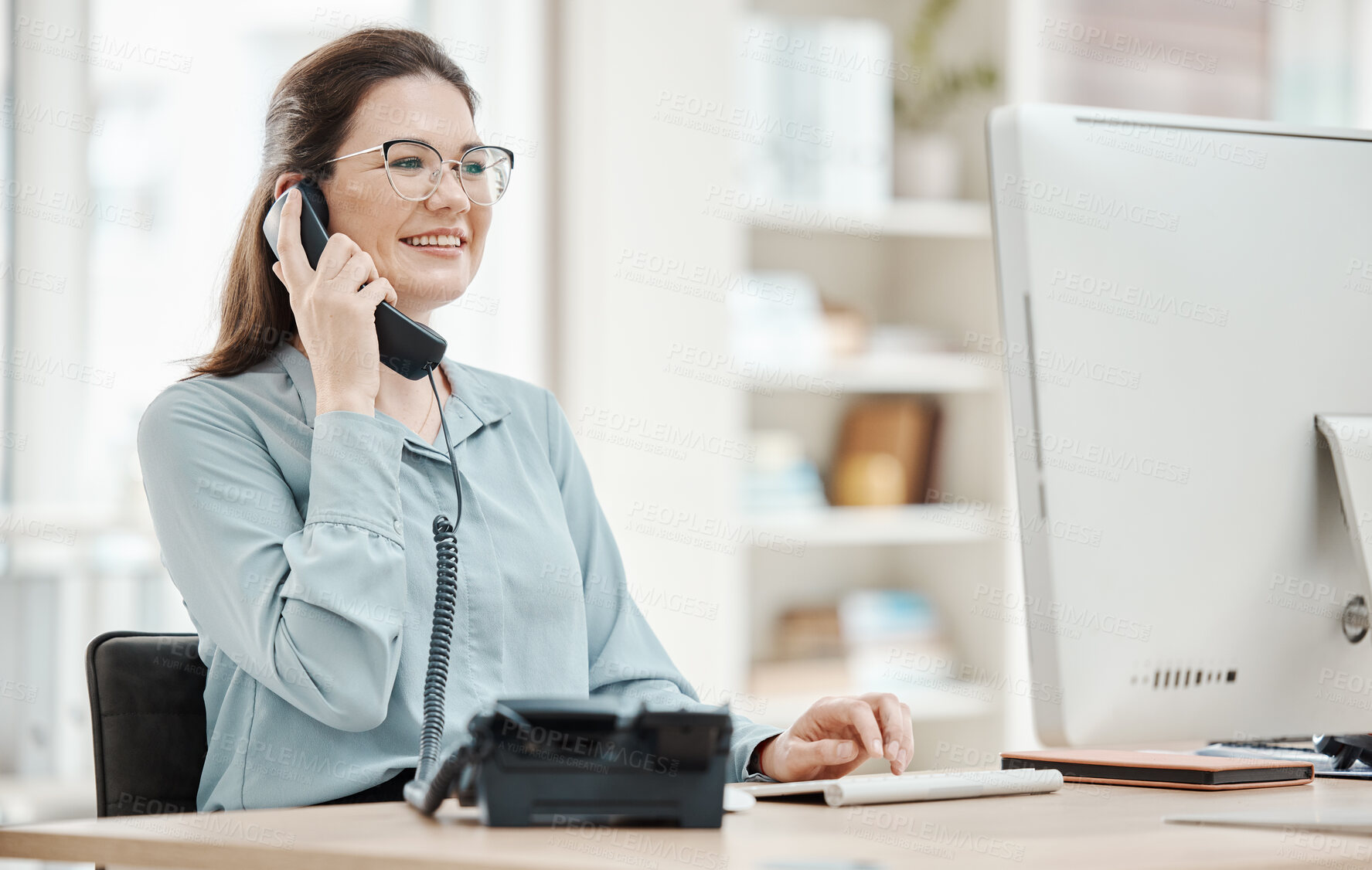 Buy stock photo Telephone, computer and business woman in office, talking or conversation. Landline, receptionist and happy female from Canada in phone call, discussion or work call on desk in company workplace.