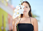 Beauty, flower and portrait of girl in city standing in urban road, orchid in hand. Fashion, cosmetics and creative shot of young Asian woman with natural beauty enjoying summer, weekend and holiday