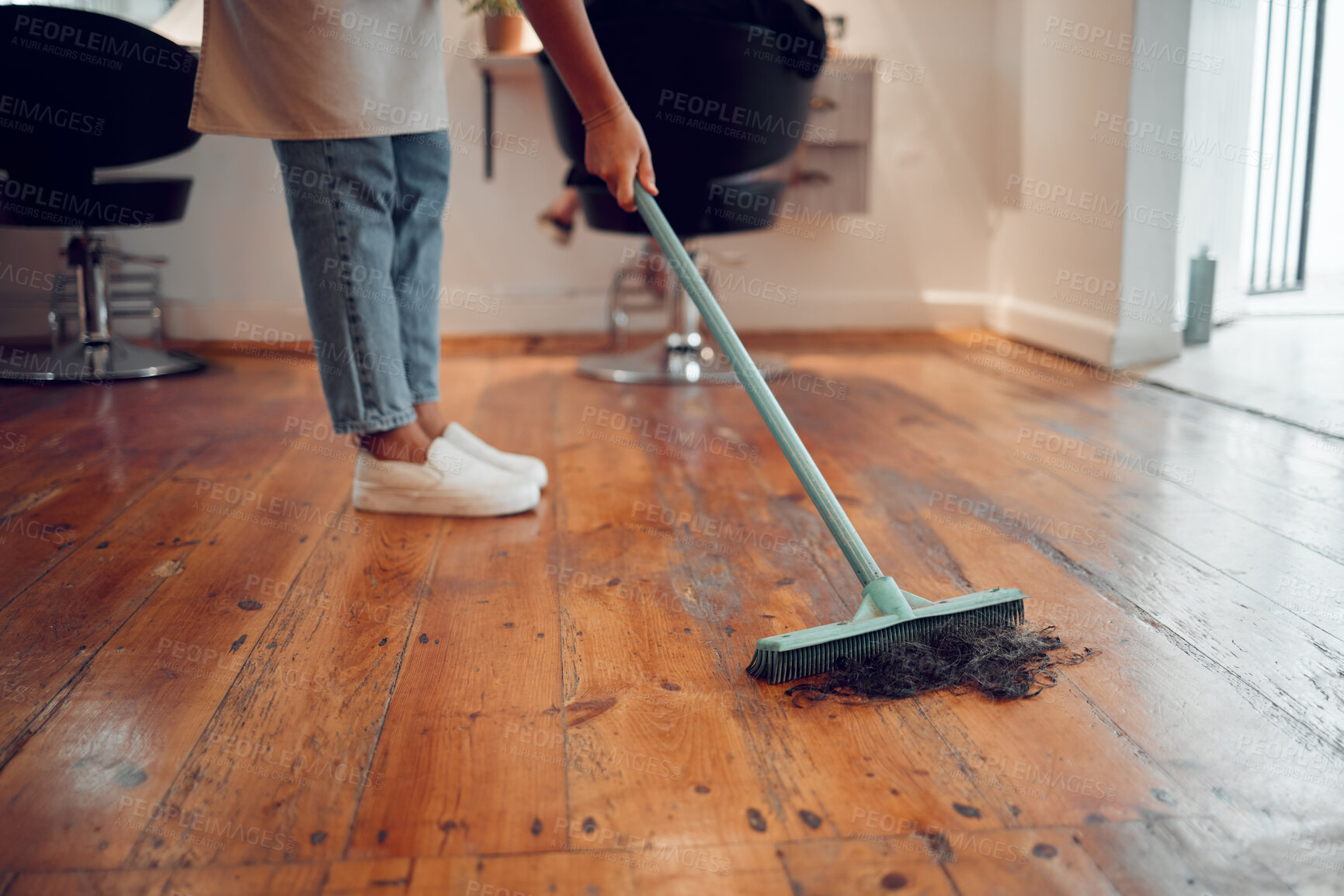 Buy stock photo Hairdresser woman, sweeping hair and cleaning salon or barbershop wooden floor after cutting a hairstyle or doing a trim. Feet of female worker with broom for dirt, dust and mess for clean workplace 