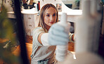 Shelf, woman and gloves in salon with product, spray or shampoo in hair care boutique. Hairdresser, small business owner and female barber from Canada in store or shop looking at cosmetic products.

