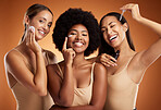 Skincare, beauty and women with product for face against an orange studio background. Portrait of a model group with oil, cream and cotton pad for skin health, wellness and care of body together
