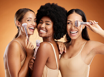 Buy stock photo Makeup, beauty and women with brush for cosmetics against a brown mockup studio background. Face portrait of happy, smile and young model group with product for facial foundation and skincare