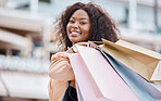 Happy, fashion and black woman shopping in a city for retail sale deals, promotions on clothes and discounts on bags. Smile, store and African customer buying clothing with freedom in a luxury mall